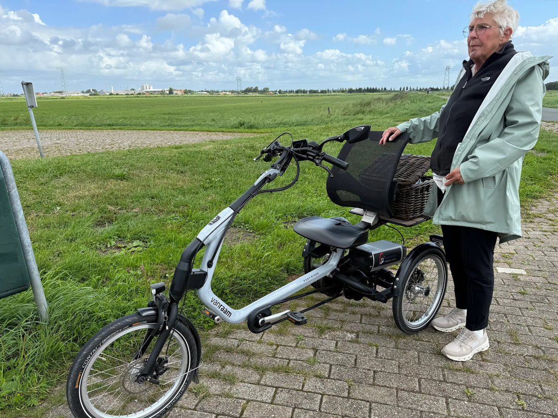 Foto van een mevrouw die naast een driewielfiets van Van Raam staat. De easy rider. Een mooie foto onderweg.