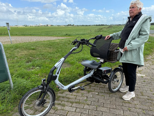 Foto van een mevrouw die naast een driewielfiets van Van Raam staat. De easy rider. Een mooie foto onderweg.